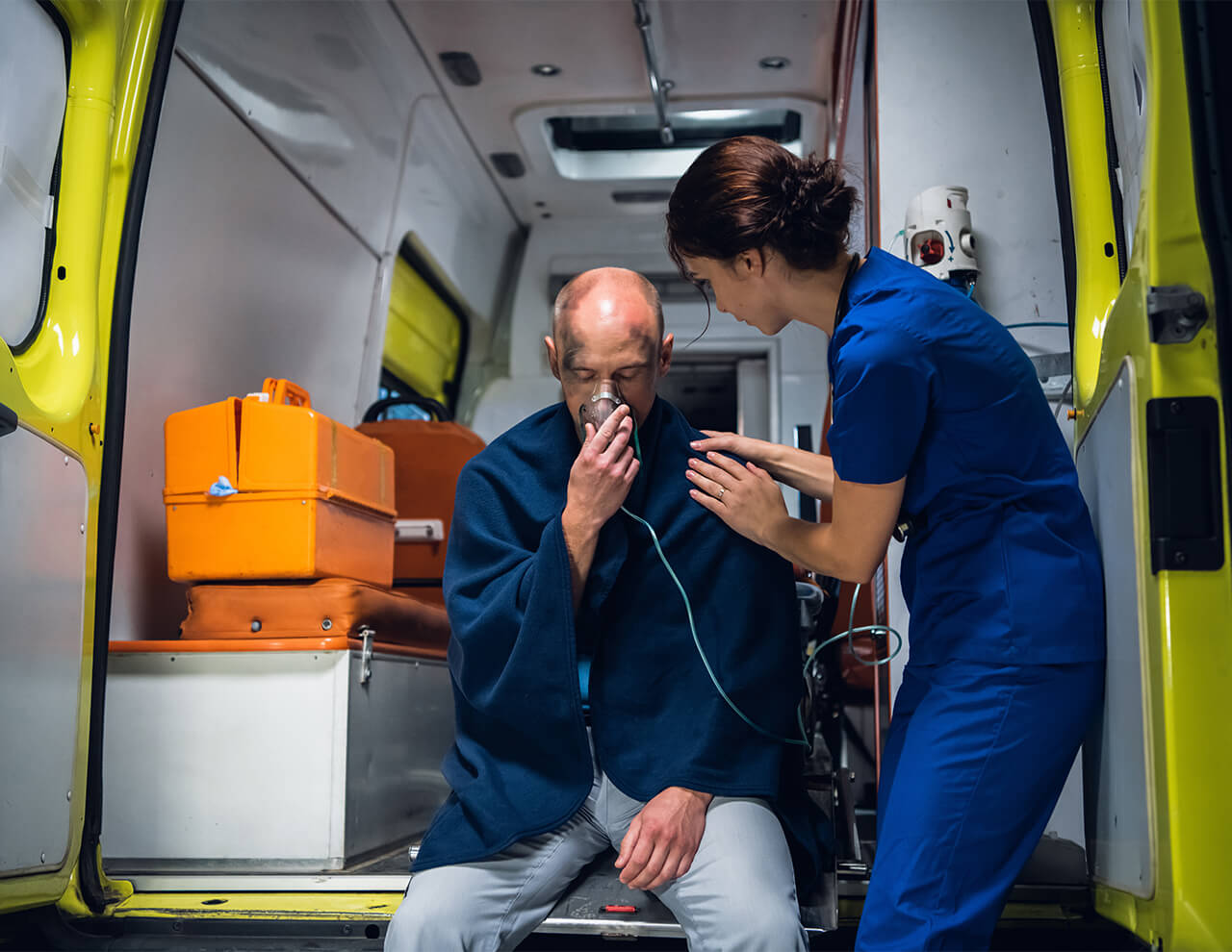 Mand der får ilt gennem en maske mens en kvinde hjælper ham. Oxygen som lægemiddel til iltbehandling i healthcare på sygehuse 